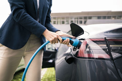 Female entrepreneur plugging charger in electric car