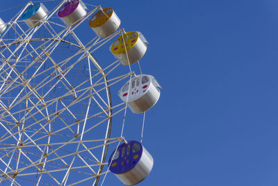 Low angle view of ferris wheel against clear blue sky