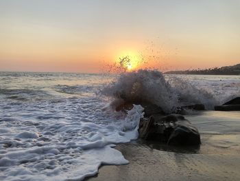Sea waves splashing on shore during sunset