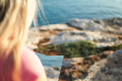 Midsection of woman on rock at beach