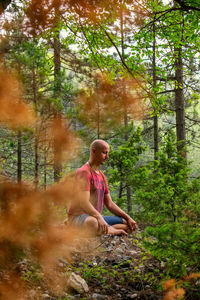 Full length of man sitting on land in forest