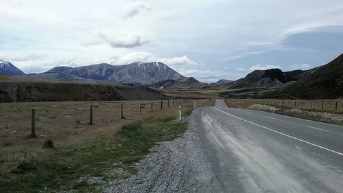 Road by mountains against sky