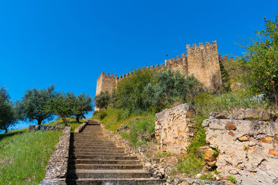 Steps amidst old building against clear blue sky