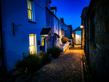 Street amidst buildings against blue sky at night