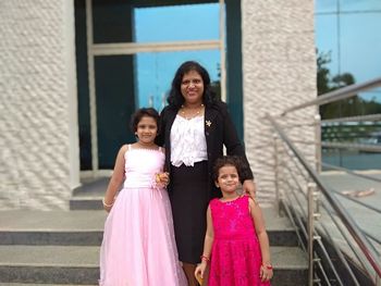 Portrait of smiling woman with daughters standing on steps