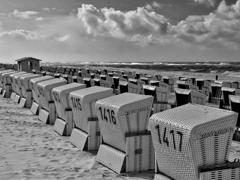 Hooded chairs on beach against sky