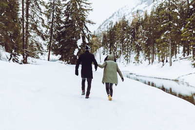 Rear view of women walking on snow covered trees