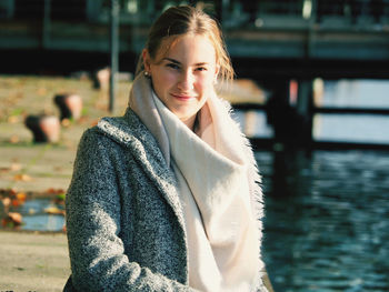 Portrait of teenage girl wearing warm clothing while standing against lake