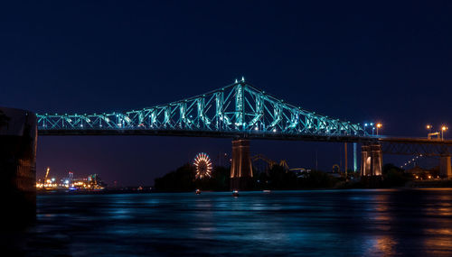 Illuminated bridge over river at night