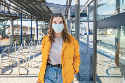 Portrait of teenage girl wearing mask while standing at entrance