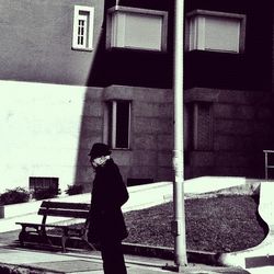 Rear view of woman standing on bench against building