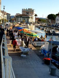 People on boats in city against sky