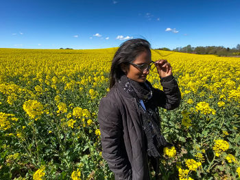 Woman standing by yellow flowers on field