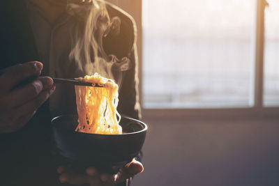 Close-up of hand holding bowl of noodles