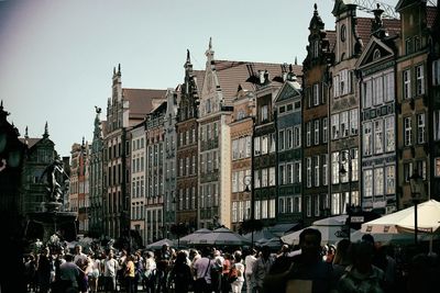 People on street amidst buildings in town against sky