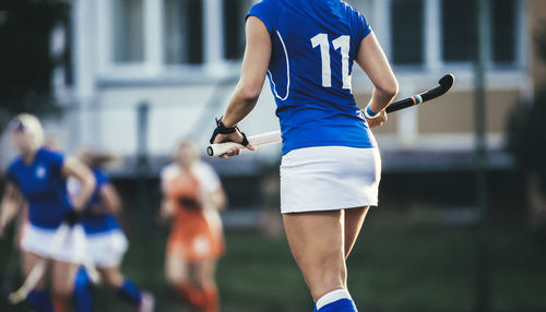 Midsection of hockey player holding bat while walking in stadium