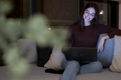 Portrait of young woman sitting on sofa at home