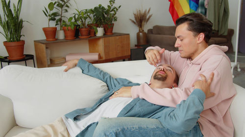 Gay couple embracing sitting on sofa at home