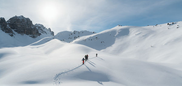 People skiing on snowcapped mountain against sky