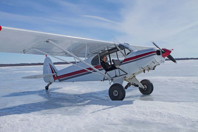 Airplane on snowy field against sky