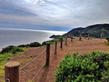 Scenic view from overlook with post barrier of sea against sky