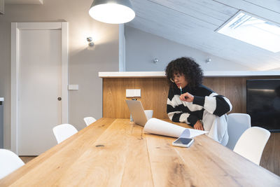 Thoughtful businesswoman looking at laptop in office