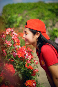 Side view of a young woman against red flowering plants