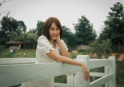 Portrait of young woman standing against trees