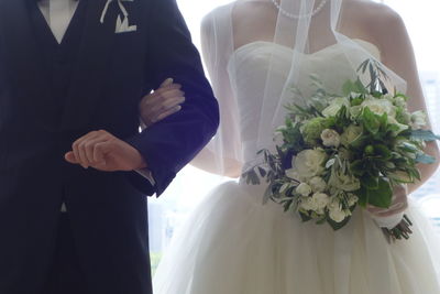 Midsection of bride and groom holding hands