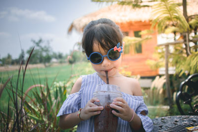 Portrait of cute girl having drink while standing outdoors