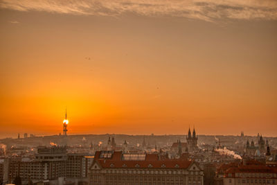 Prague tv tower at sunrise wirh roofs and birds flying