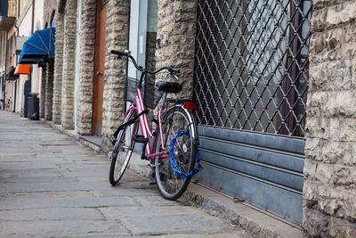 Bicycle parked on footpath against building