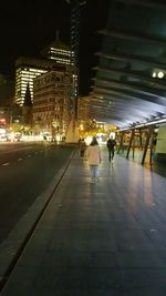 Woman standing on illuminated city street at night