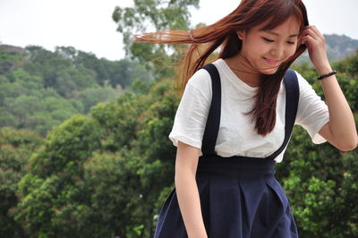 Smiling young woman against trees