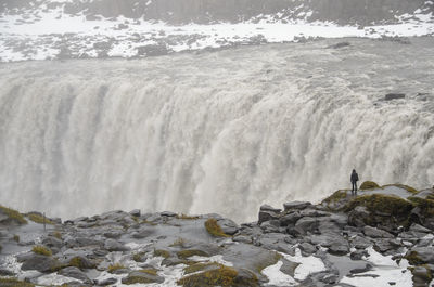 Rear view of person looking at waterfall