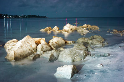 Rocks on beach by sea against sky