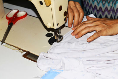 Midsection of woman working on sewing machine