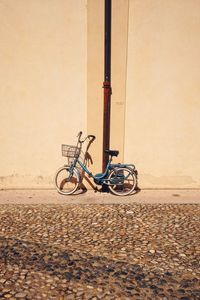 Bicycle parked against wall at cobbled street