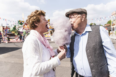 Senior couple on fair eating together cotton candy