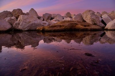 Reflection of rocks in lake against sky