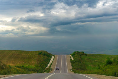 Road passing through landscape against sky