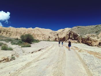 Rear view of people walking on road against mountain