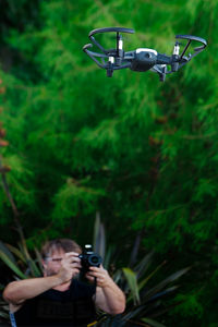 Man photographing drone against tree