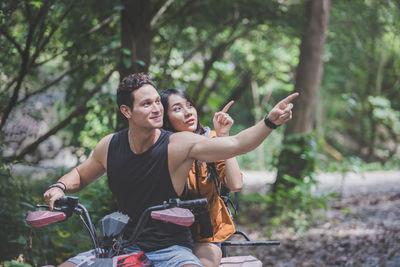 Man with woman sitting on quadbike in forest