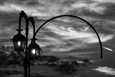 Low angle view of illuminated street light against cloudy sky