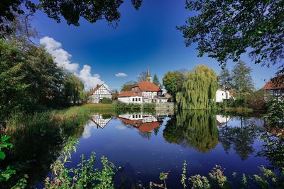 Reflection of trees and buildings in lake against sky