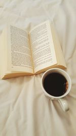 High angle view of tea cup by book on bed at home
