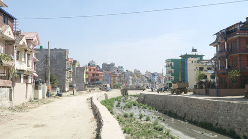 Road amidst buildings in city against sky