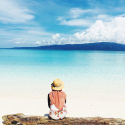 Rear view of woman on beach against sky