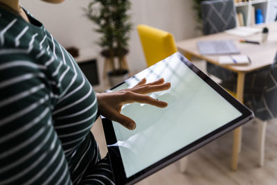 Young businesswoman touching screen of digital tablet at work place